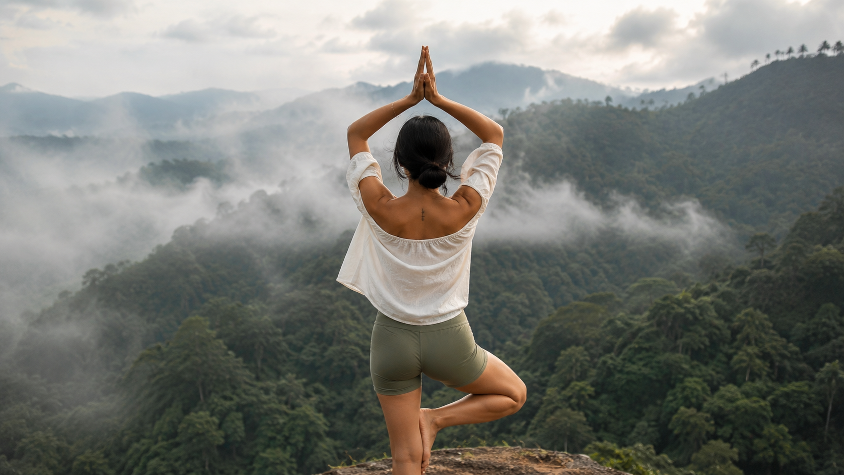Mila in tree pose overlooking misty mountains at dawn